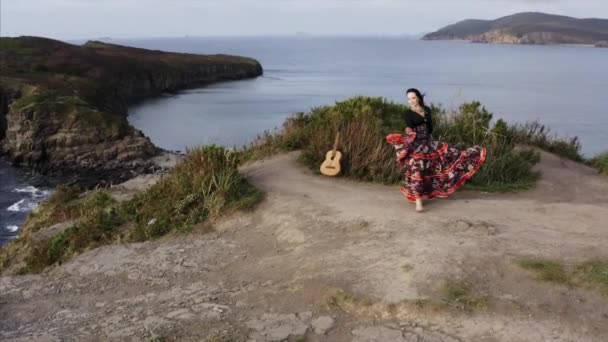 海の上の高い崖の上で踊る美しいドレスでジプシー女性の空中パノラマビュー — ストック動画