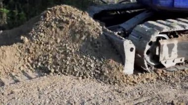 Güçlü kazıcı güneşli bir günde toprakla çalışıyor.
