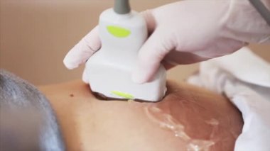 Doktorun eldiven içinde eldiven tutarken ve hamile kadının ultrason taramasını yaparken yakın görüntüsü.