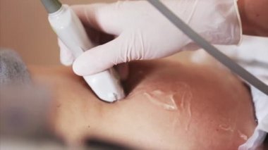 Doktorun eldiven içinde eldiven tutarken ve hamile kadının ultrason taramasını yaparken yakın görüntüsü.