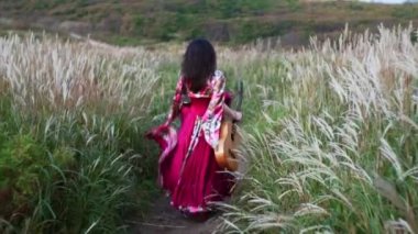 Mutlu esmer çingene kadın gitarıyla sahada koşuyor ve dans ediyor. 