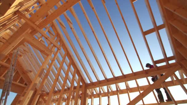 建筑工人在未完工的框架结构房屋内部施工 屋面为木制梁 背景为蓝天墙 — 图库视频影像