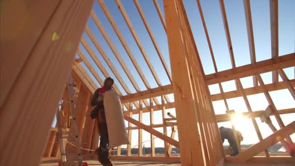 Builders working at unfinished frame house interior with wooden beams of roof and walls with blue sky on background — Stock Footage Builders Working Unfinished Frame House Interior Wooden Beams Roof Walls Stock Video