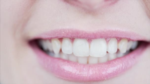 唇に淡いピンクの口紅と美しい白い歯を持つ女性の口のマクロビューと笑顔 — ストック動画