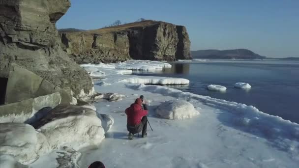 작가가 눈덮인 해안선 과높은 절벽에서 사진을 — 비디오