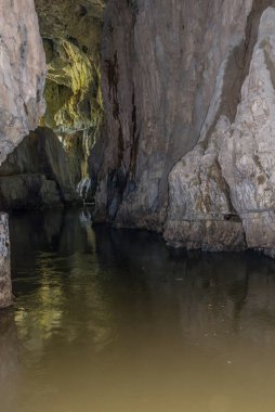 Mağaradaki bir nehir. Ziyaretçilerin bakış açısından gerçek duygularla aydınlatma. Slovenya. Bir mağaranın ağzında parlıyor.