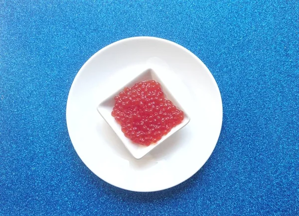 Caviar Vermelho Peixe Salmão Uma Chapa Branca Fundo Azul — Fotografia de Stock