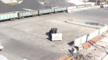 İskele tarafında yükleyici çalışması, kargo sınırlarını oluşturmak için beton blokları hareket ettiriyor.