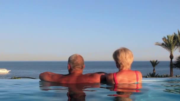 Красивая молодая пара мужчина и женщина отдыхают на курорте в бассейне — стоковое видео