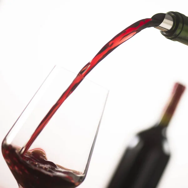 Gieten van rode wijn in wijnglas uit groene fles — Stockfoto
