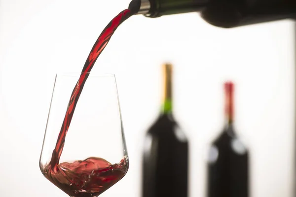 Verser du vin rouge dans un verre à vin à partir d'une bouteille verte — Photo