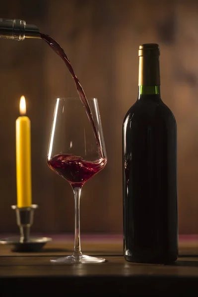 Verser du vin rouge dans un verre à vin à partir d'une bouteille verte — Photo