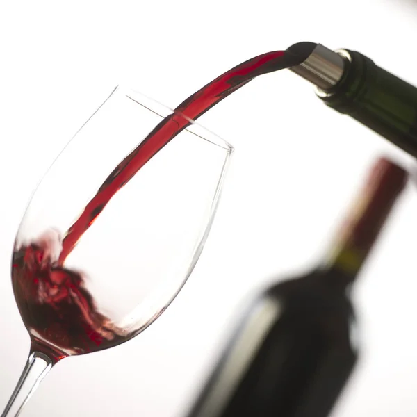 Gieten van rode wijn in wijnglas uit groene fles — Stockfoto