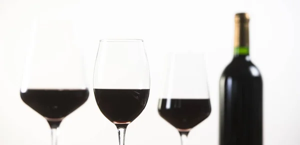 Бутылка красного вина и три стакана на белом фоне — стоковое фото
