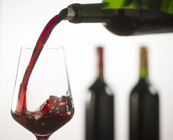 Verser du vin rouge dans un verre à vin à partir d'une bouteille verte — Photo