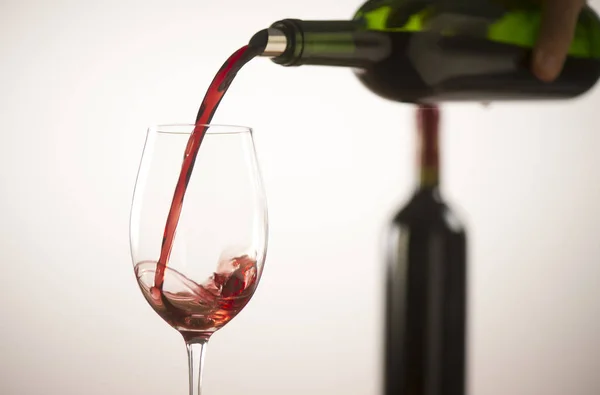 Verser du vin rouge dans un verre à vin à partir d'une bouteille verte — Photo