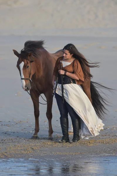 Jovencita montando un caballo en la playa temprano en la mañana — Foto de Stock