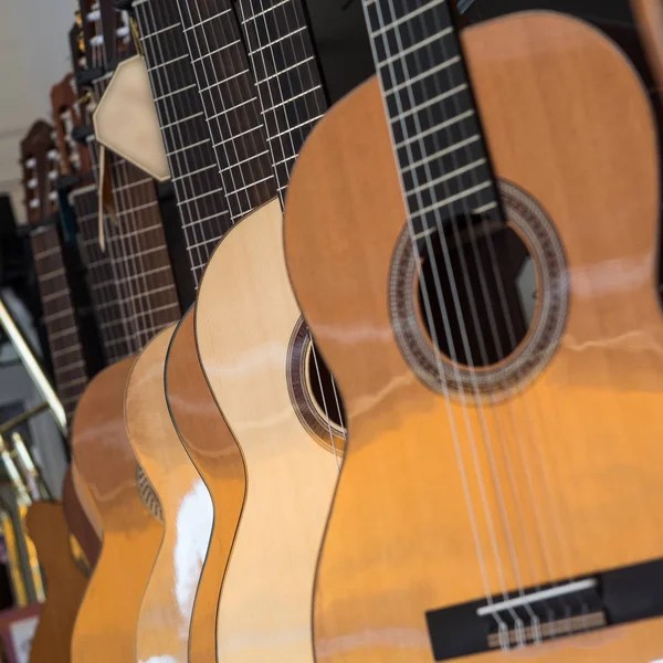 Muchas guitarras clásicas colgando de la pared en la tienda —  Fotos de Stock