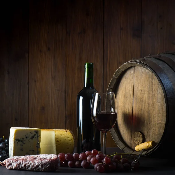 Copo de queijos de vinho tinto uvas e barril em madeira marrom — Fotografia de Stock