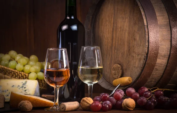 Glasses of rose and white wine cheeses grapesand barrel brown background — Stock Photo, Image