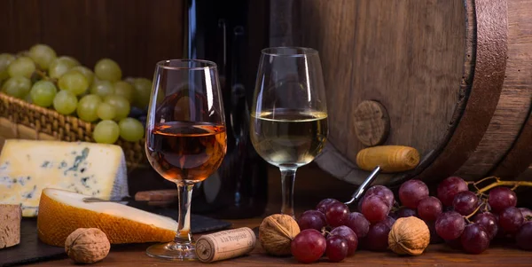 Copos de rosa e queijos de vinho branco uvas e barril fundo marrom — Fotografia de Stock