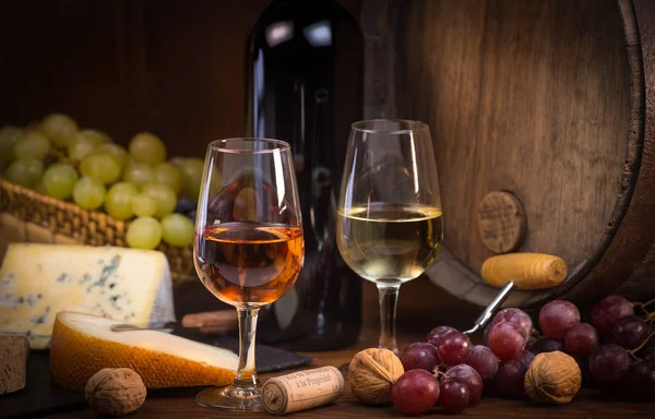 Copos de rosa e queijos de vinho branco uvas e barril fundo marrom — Fotografia de Stock