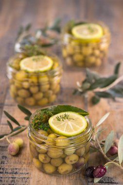 Ahşap masa üzerinde kavanoza korunmuş yeşil zeytin