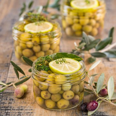 Ahşap masa üzerinde kavanoza korunmuş yeşil zeytin