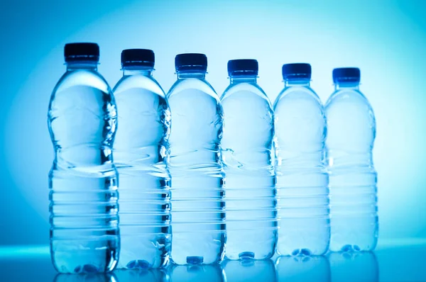Plastikflaschen mit Wasser isoliert auf blau — Stockfoto