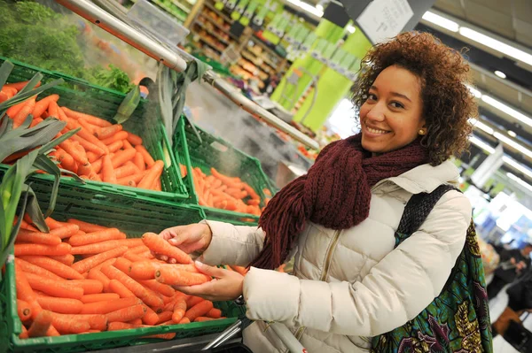 Женщина покупает морковь и еду в супермаркете — стоковое фото