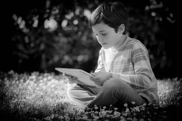 孩子读一本书坐在草地上 — 图库照片