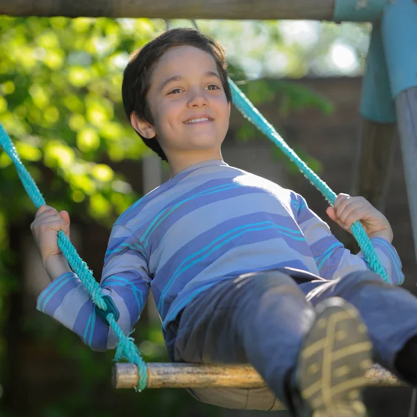 Niño jugando con un columpio en un parque —  Fotos de Stock