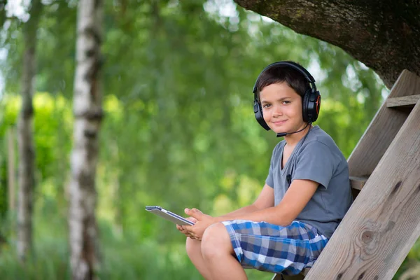 戴着耳机户外计算机上玩的孩子 — 图库照片
