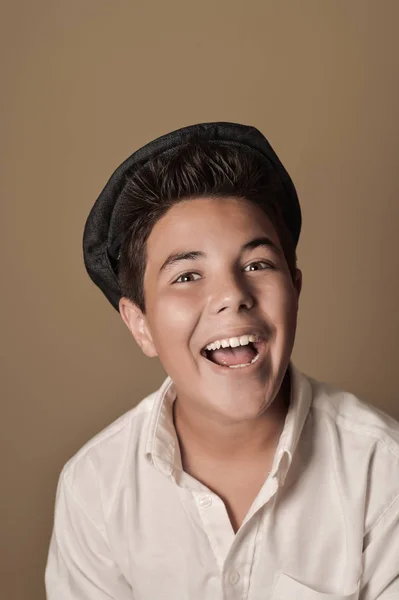 Laughing boy with a cap on a brown background — Stok Foto