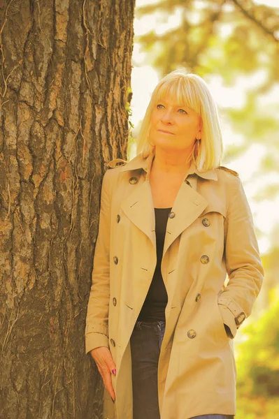 Retrato de una mujer mayor sonriente apoyada en un árbol — Foto de Stock