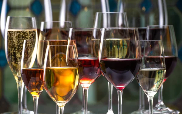 Champán, blanco y rojo gana y bebe en copas sobre fondo de vidriera —  Fotos de Stock