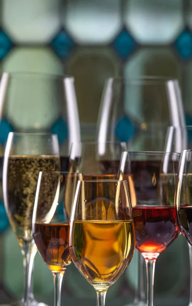 Champagne, bianco, rosa e rosso vince e beve in bicchieri su fondo di vetro colorato — Foto Stock