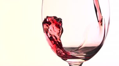 Beyaz arkaplana karşı bardağa kırmızı şarap dökmek