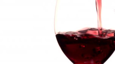 Beyaz arkaplana karşı bardağa kırmızı şarap dökmek