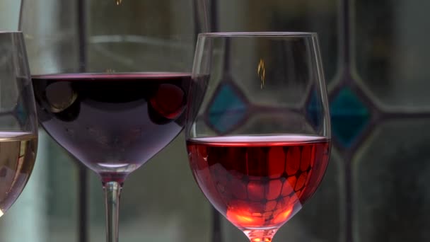 Champagner, weiße, rosa und rote Siege und Getränke in Gläsern auf Glasmalerei-Hintergrund — Stockvideo