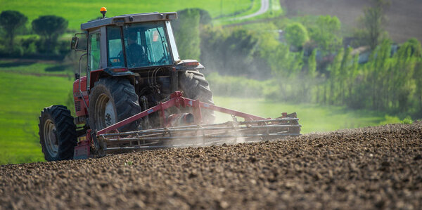 Tractor plowing field and beautiful landscape, France