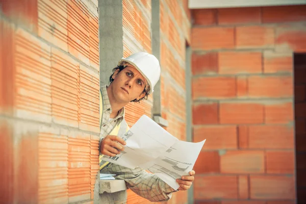 Επαγγελματίας αρχιτέκτονας μηχανικός με προστατευτικό κράνος και χαρτί σχεδιαγράμματα στο σπίτι κτίριο οικοδομής φόντο — Φωτογραφία Αρχείου