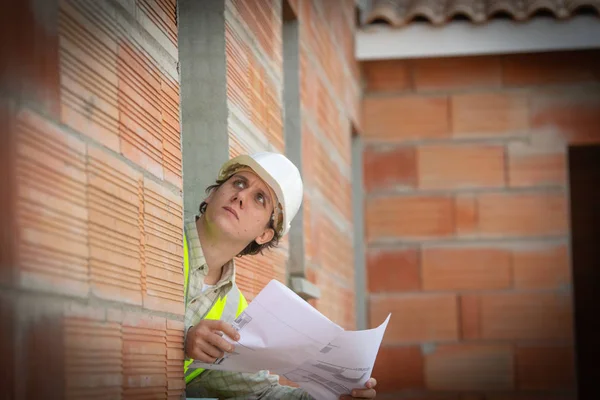Ingeniero profesional arquitecto trabajador con casco protector y planos de papel en el edificio de la casa de la construcción de fondo —  Fotos de Stock