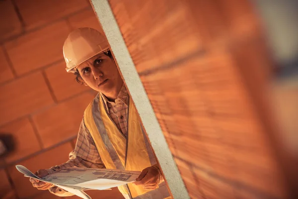 Ingeniero profesional arquitecto trabajador con casco protector y planos de papel en el edificio de la casa de la construcción de fondo —  Fotos de Stock