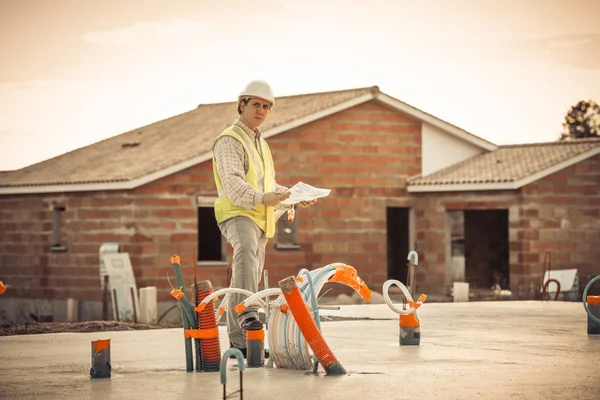 Ingeniero profesional arquitecto trabajador con casco protector y planos de papel en el edificio de la casa de la construcción de fondo —  Fotos de Stock