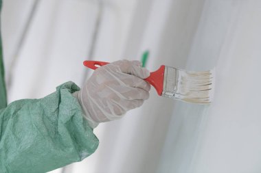 Tamirci adam duvar boyuyor, dişlerini fırçalıyor.