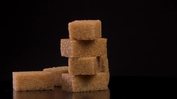 Cubos de azúcar morena girando sobre fondo blanco — Vídeo de stock