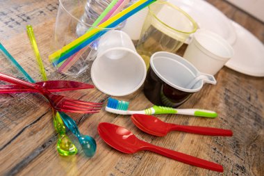 Günlük plastik atıklar, çeşitli plastik kaplar, ahşap arka planda çevre koruması.