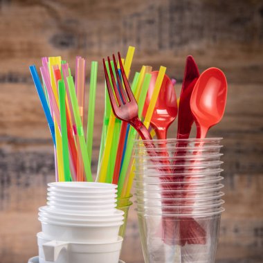 Günlük plastik atıklar, çeşitli plastik kaplar, ahşap arka planda çevre koruması.