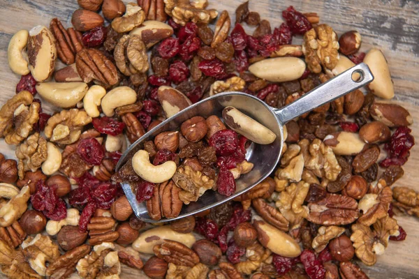 Mixed nuts and dried fruits in wooden bowl on wood background, copy space